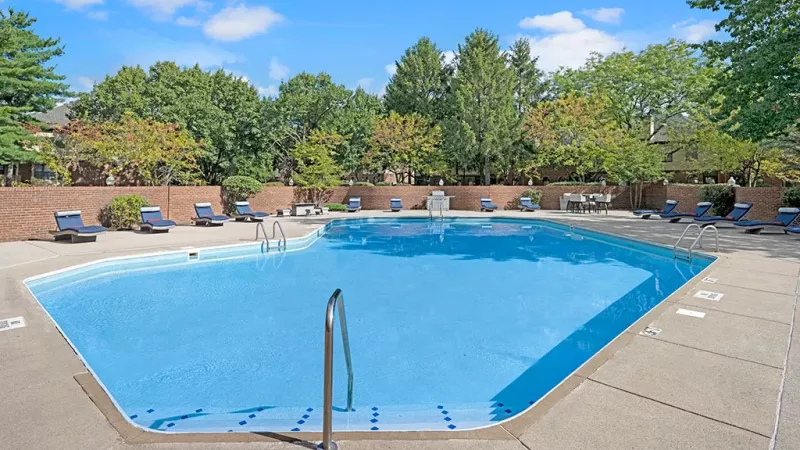 Sparkling swimming pool with lounge chairs under pergolas for residents to enjoy.