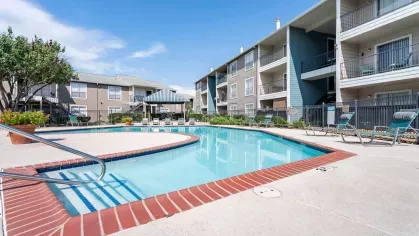 Sparkling resort style swimming pool with lounge chairs surrounding.