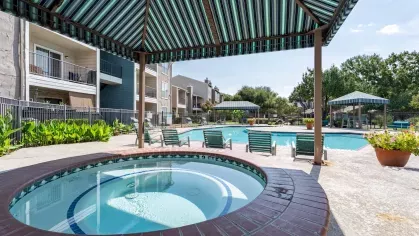 Hot tub located under a cabana near the sparkling swimming pool.
