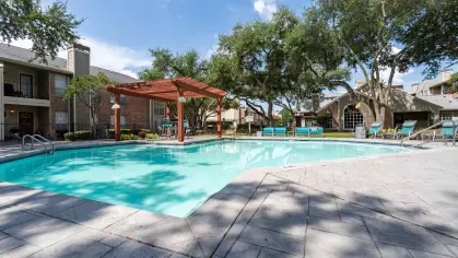 Sparkling swimming pool with lounge chairs under pergolas for residents to enjoy.