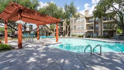 Sparkling swimming pool with lounge chairs under pergolas for residents to enjoy.