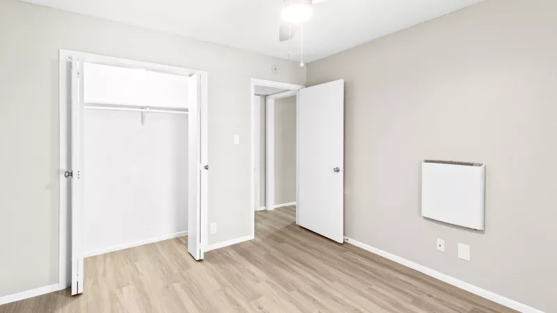 Flats at Wellington Bedroom with open closet and overhead lighting and ceiling fan.