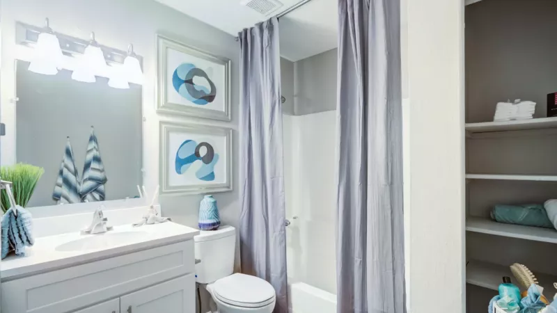 Bright, open bathroom with shower and tub combination and ample storage.
