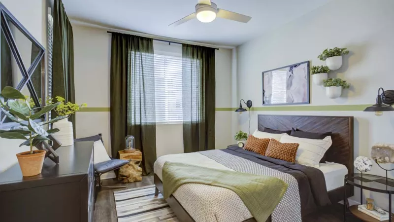 Bright, open bedroom with overhead light and ceiling fan and a large window.