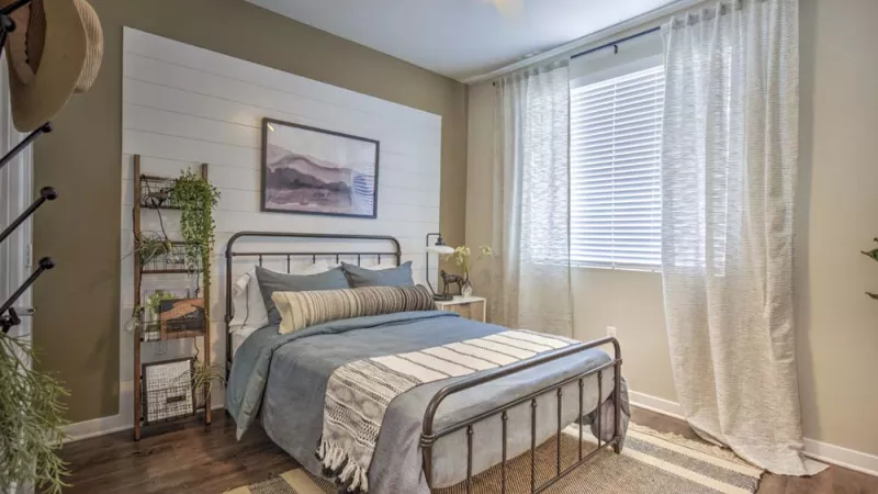 Bright, open bedroom with overhead light and ceiling fan and a large window.