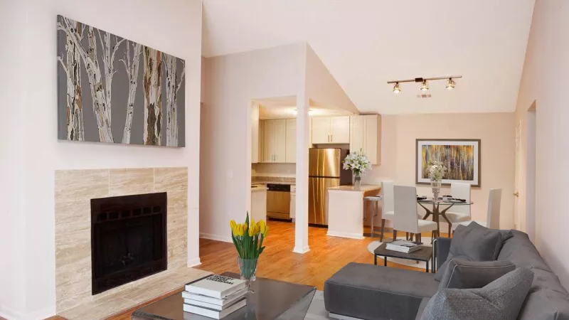 Open-concept living room with a fireplace, birch tree art, and grey sectional sofa. Adjacent dining area and kitchen.