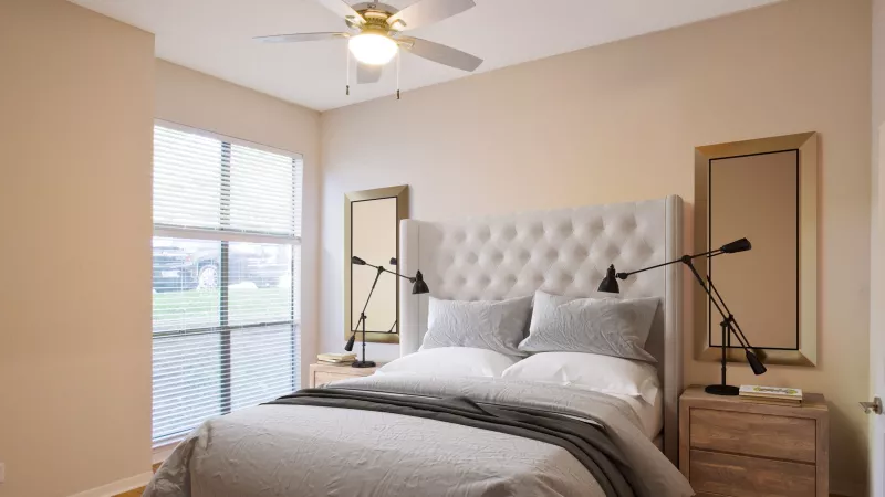 Modern bedroom with a large bed, tufted headboard, two nightstands, two mirrors, and a ceiling fan.
