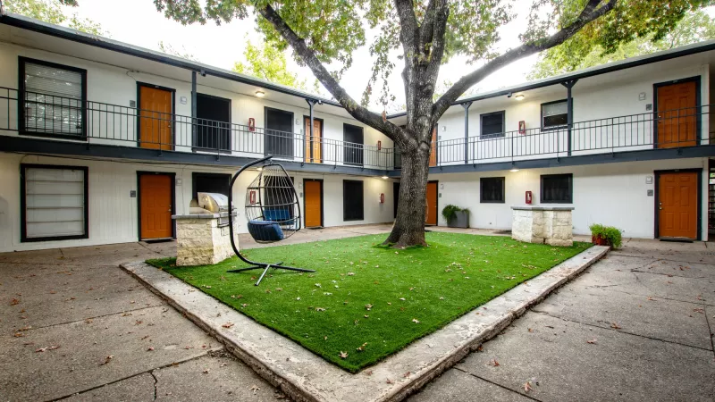 Open courtyard with large tree and bright greenery area for residents to enjoy.
