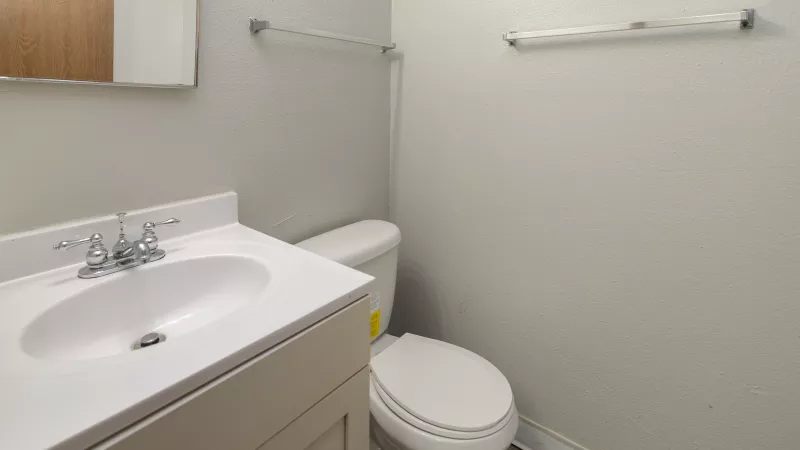 Clean bathroom with a white vanity sink, toilet, and light-colored walls.