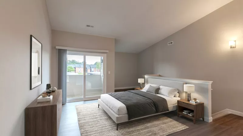 Neutral-toned bedroom with a white bed, dark wood floor, angled ceiling, and a sliding glass door to a balcony.