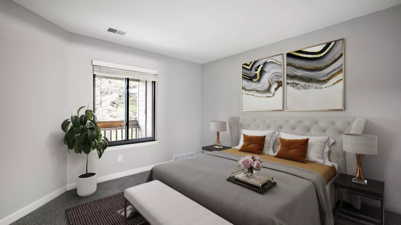 Bright, modern bedroom with a grey bed, padded headboard, abstract gold and black art, and a plant by a large window.