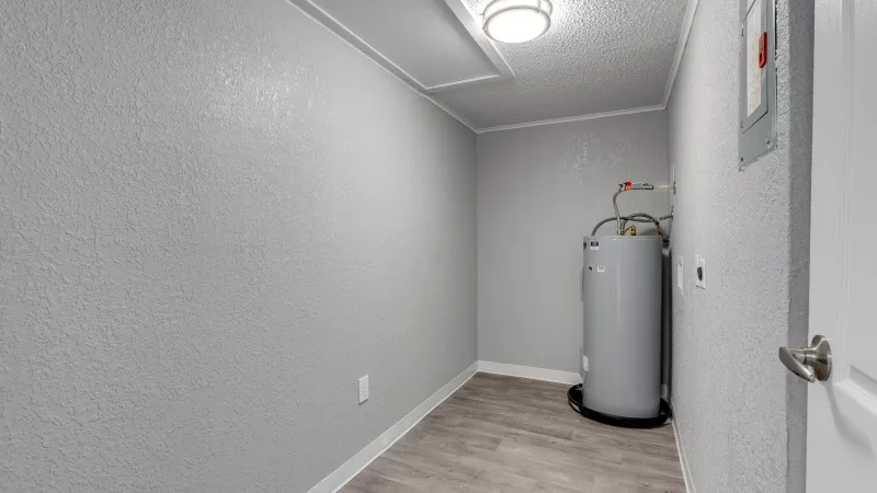 Utility closet with light gray walls, wood-look floor, a gray water heater, and an electrical panel.