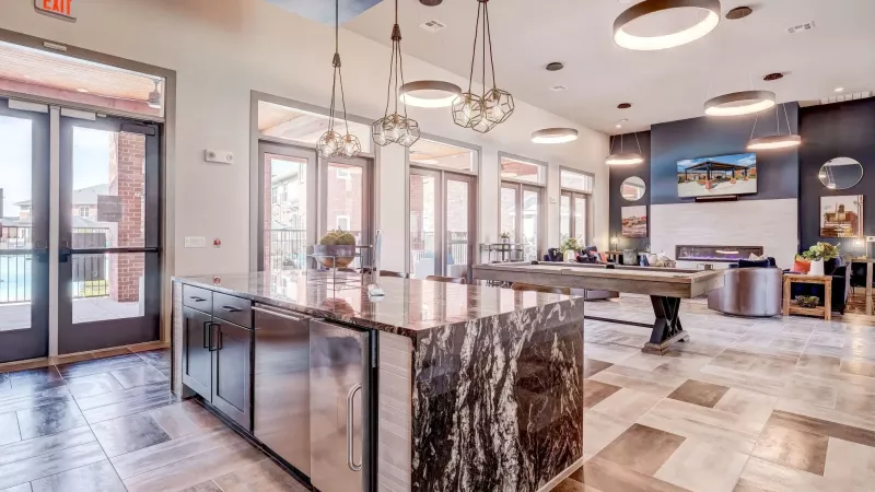 Modern common room with a marble island, tiled floor, pool table, fireplace, and flat-screen TV.