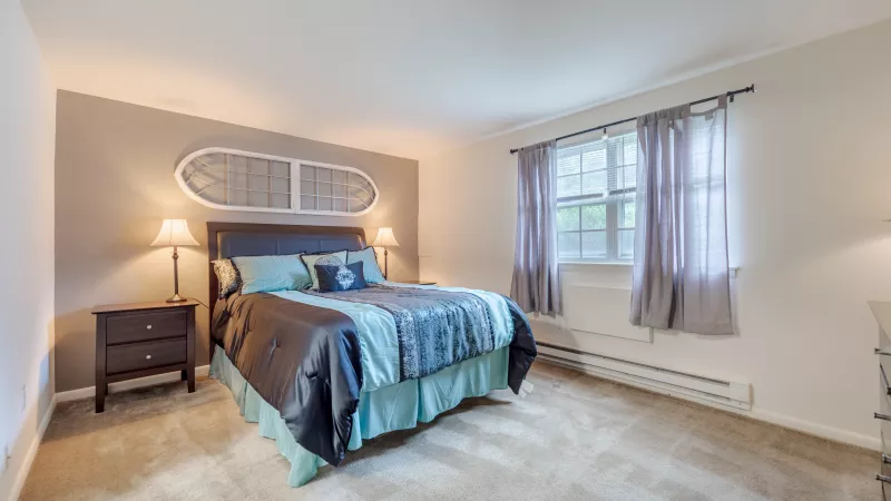 Bedroom with a queen bed featuring blue and brown bedding, two nightstands with lamps, and an oar decoration above the bed.