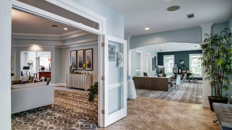 Modern apartment building lobby with light blue walls, a lounge area, and a reception desk.