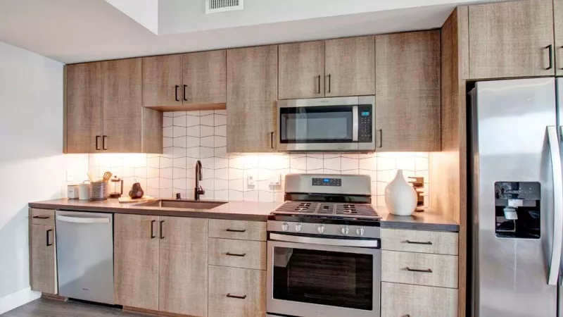 Kitchen with wood-grain cabinets, stainless steel appliances, and white backsplash.