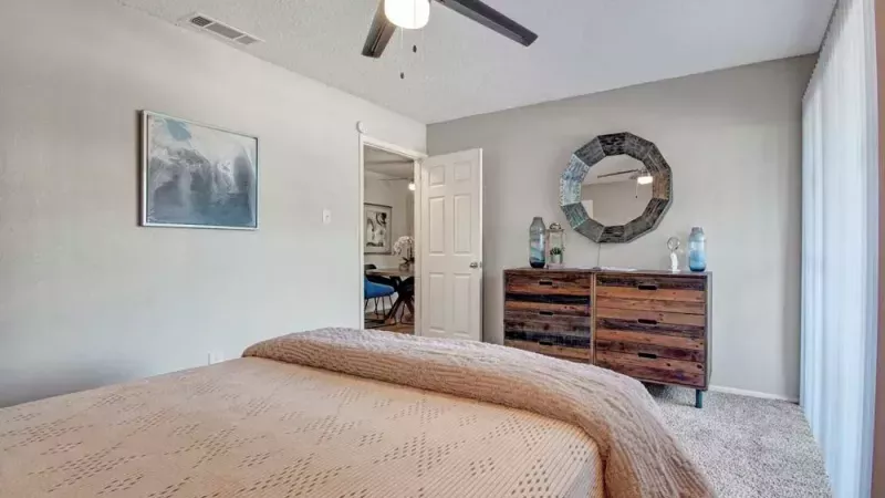 Bright bedroom with rustic wooden furniture, a decorative mirror, and soft natural lighting.