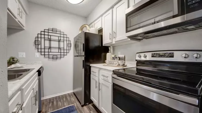 A modern kitchen with white cabinets, black appliances, and a decorative wall accent.
