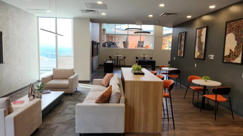 A modern clubhouse lounge with a cozy seating area and large windows offering city views.