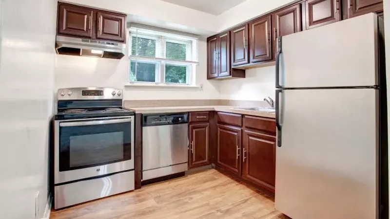 A modern kitchen with dark brown cabinets, stainless steel appliances, and a window providing natural light.