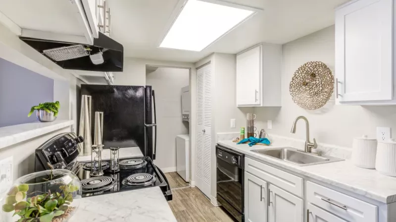 A modern kitchen with white cabinets, stainless steel appliances, and a marble countertop adorned with decorative elements.