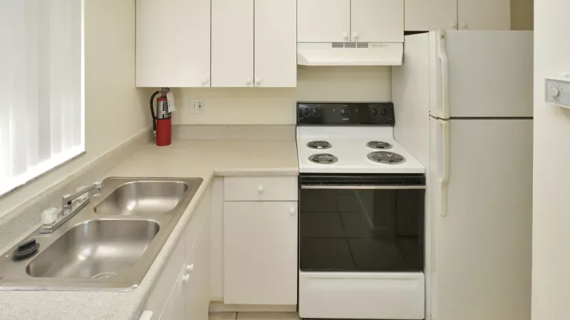 A modern kitchen with white cabinets, a refrigerator, and an electric stove, featuring a clean and practical layout.