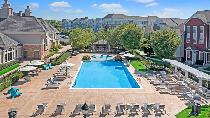 Aerial view of the expansive resort-style pool surrounded by lounge chairs, umbrellas, and lush landscaping at The Grove Somerset Apartments.