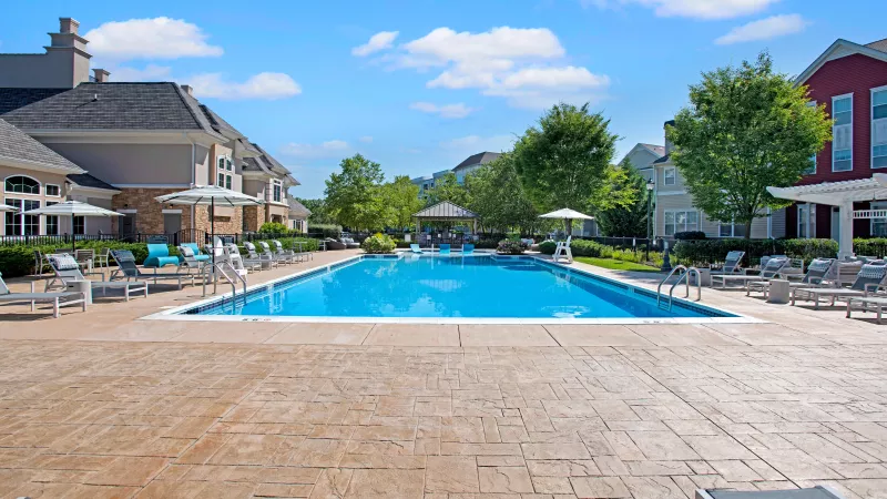 Front-facing view of the pristine swimming pool and surrounding greenery, offering a relaxing outdoor experience for residents at The Grove Somerset Apartments.