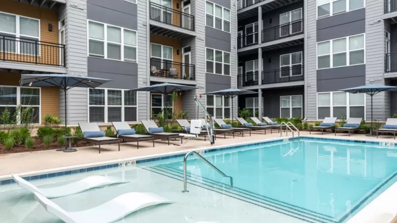 A luxurious resort-style pool surrounded by lounge chairs and umbrellas, providing a relaxing retreat for residents at The Everly Luxury Apartments.