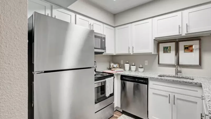 Modern kitchen with stainless steel appliances, white cabinets, and granite countertops.