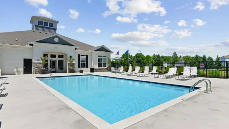 A sparkling blue swimming pool in front of the clubhouse, offering resort-style relaxation with ample seating.