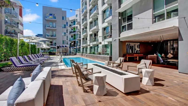Outdoor social space with fire pit, string lights, and poolside seating at The Pacific Luxury Apartments.