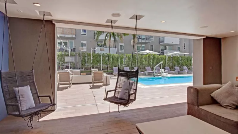 Cozy indoor-outdoor seating with swing chairs and pool views at The Pacific Luxury Apartments.