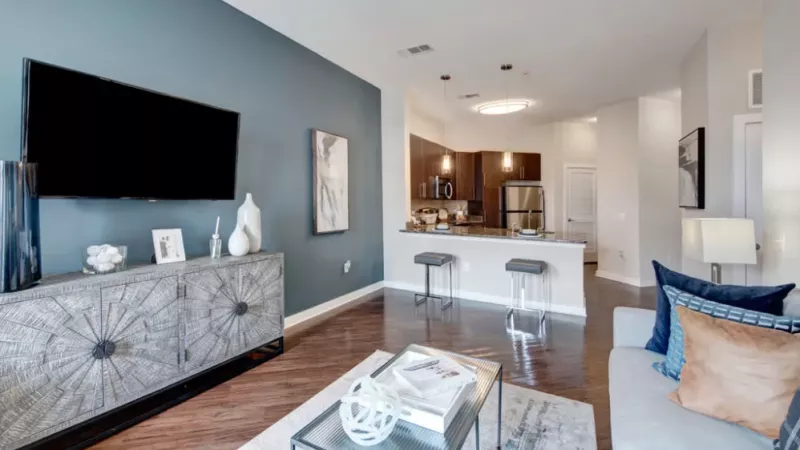 A modern living room with a blue accent wall, a large TV, and a stylish sofa adorned with decorative pillows.