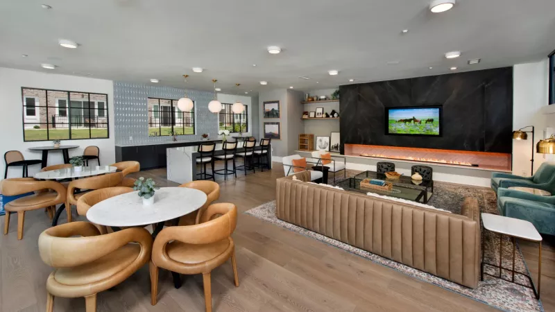 A stylish clubhouse with lounge seating, a fireplace, a TV, and a mix of dining and bar seating.