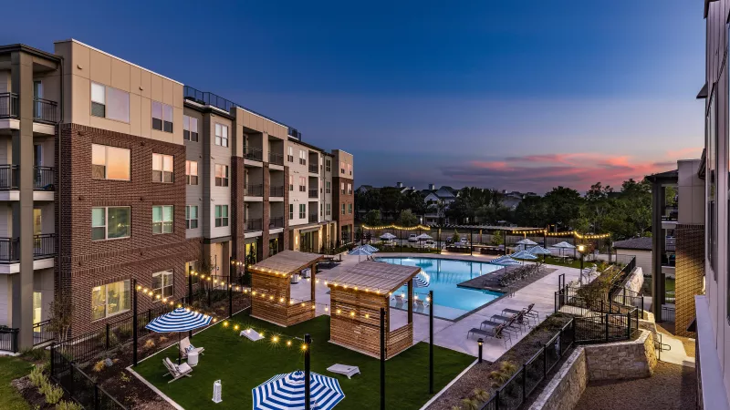 String lights illuminate the cabanas and landscaped lounge areas, creating an inviting atmosphere as the sun sets.