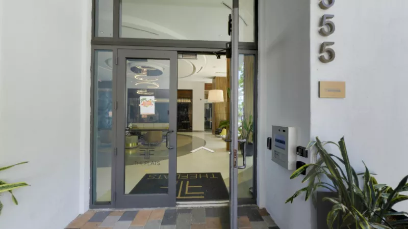 Welcoming entrance to The Flats at City Place Luxury Apartments, featuring modern glass doors, stylish interior decor, and the property's signature logo for a sophisticated first impression.