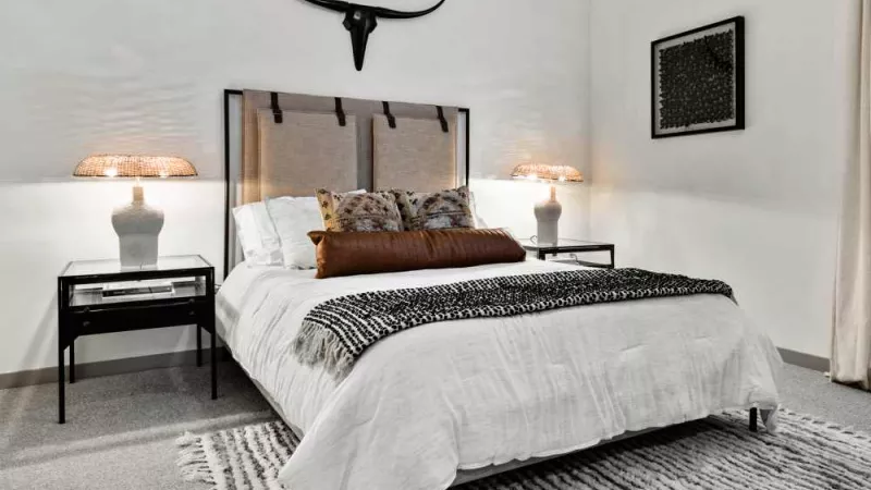 A chic bedroom with a rustic headboard, elegant lighting, and a bold decorative accent above the bed.