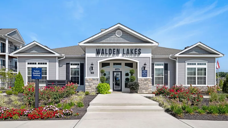 Front view of the Walden Lakes leasing office with manicured flower beds, signage, and a welcoming entry path.