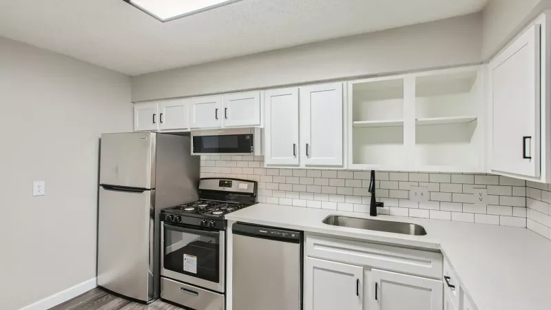 Contemporary kitchen at City View at Mueller with white cabinetry, stainless steel appliances, subway tile backsplash, and a black faucet.