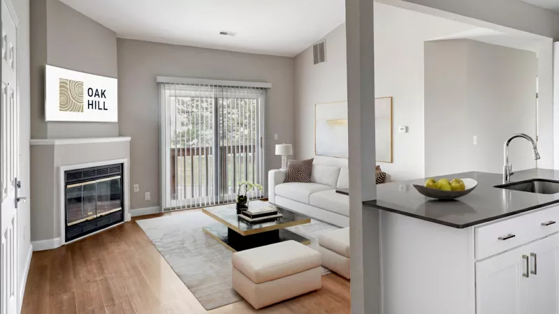 Spacious open-plan apartment with a living room, fireplace, white sofa, and a kitchen island with a sink.