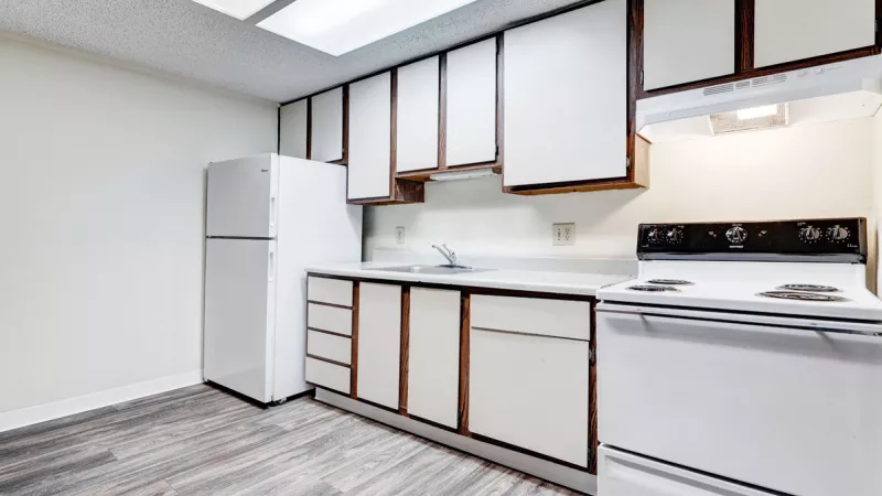 Clean, empty kitchen featuring white appliances, cabinets with dark trim, and a patterned grey floor.