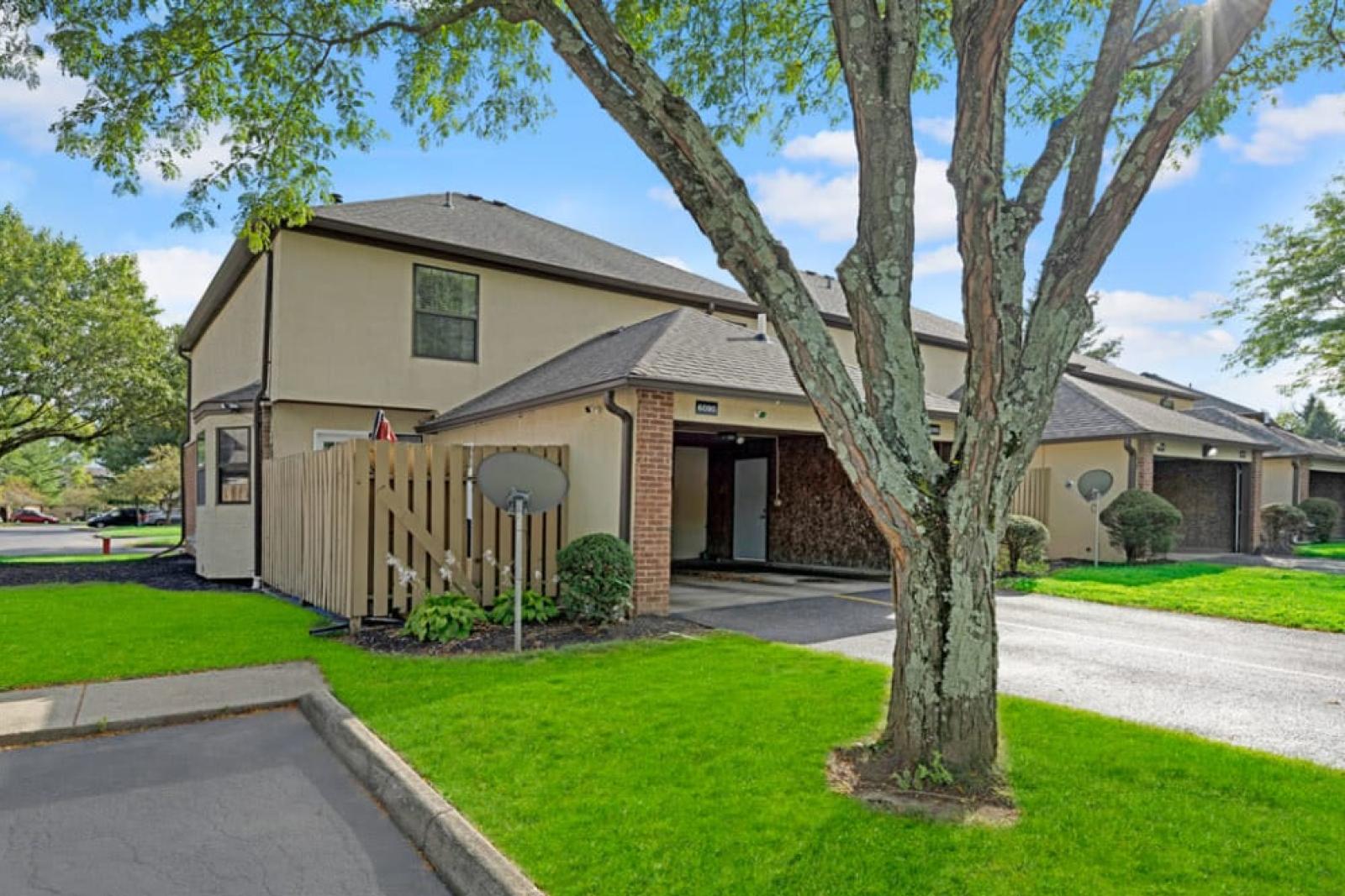 The exterior view of a townhome with a private fenced patio area and lush green grass.
