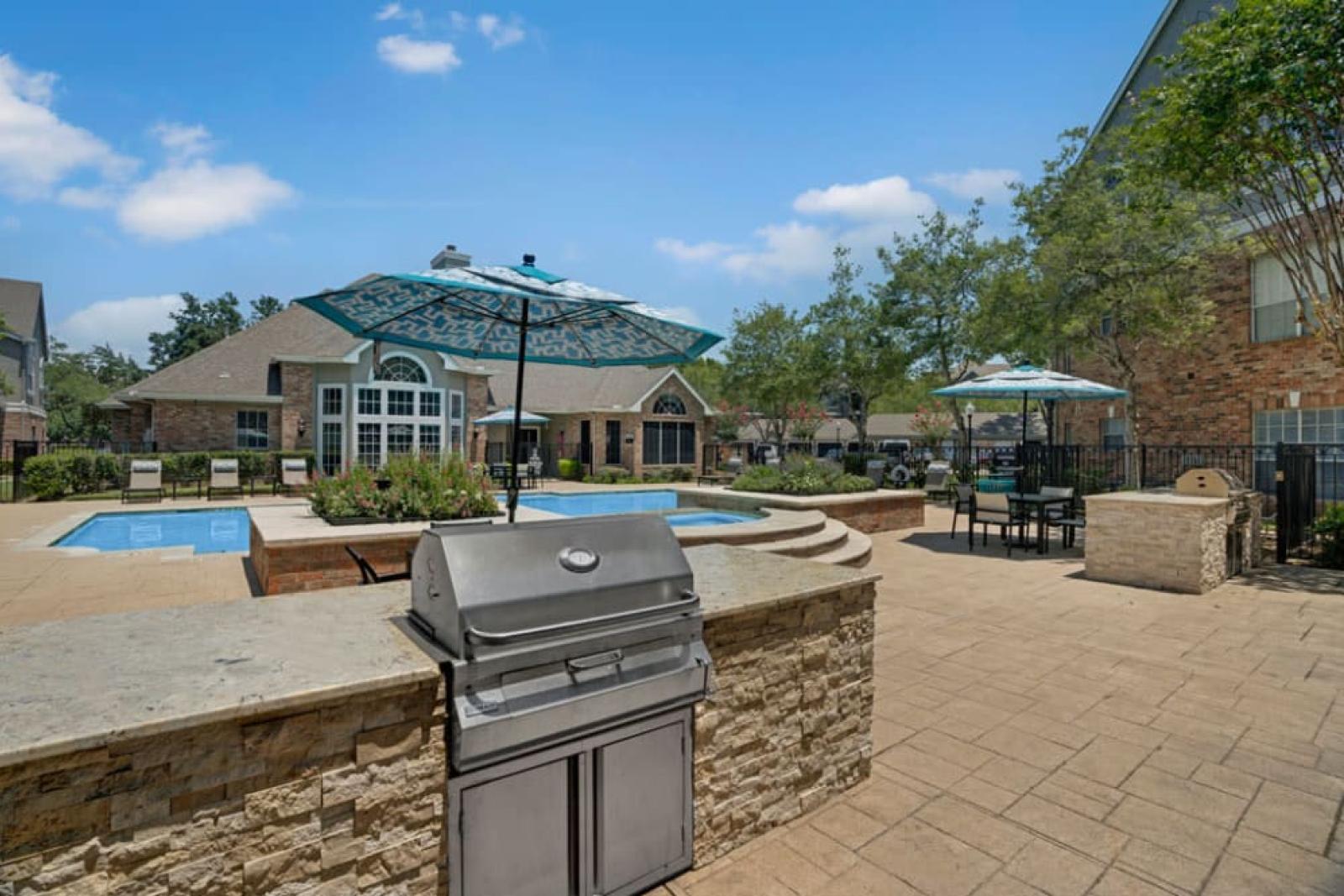 Outdoor grilling station with adjacent seating areas and a view of the pool.