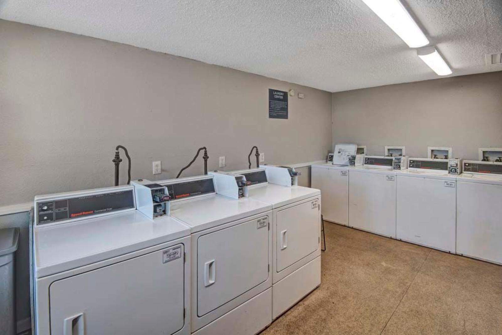 A clean and well-lit laundry room equipped with multiple washers and dryers for resident use. This image highlights the convenient on-site laundry facilities at Broadview Oaks Apartments.