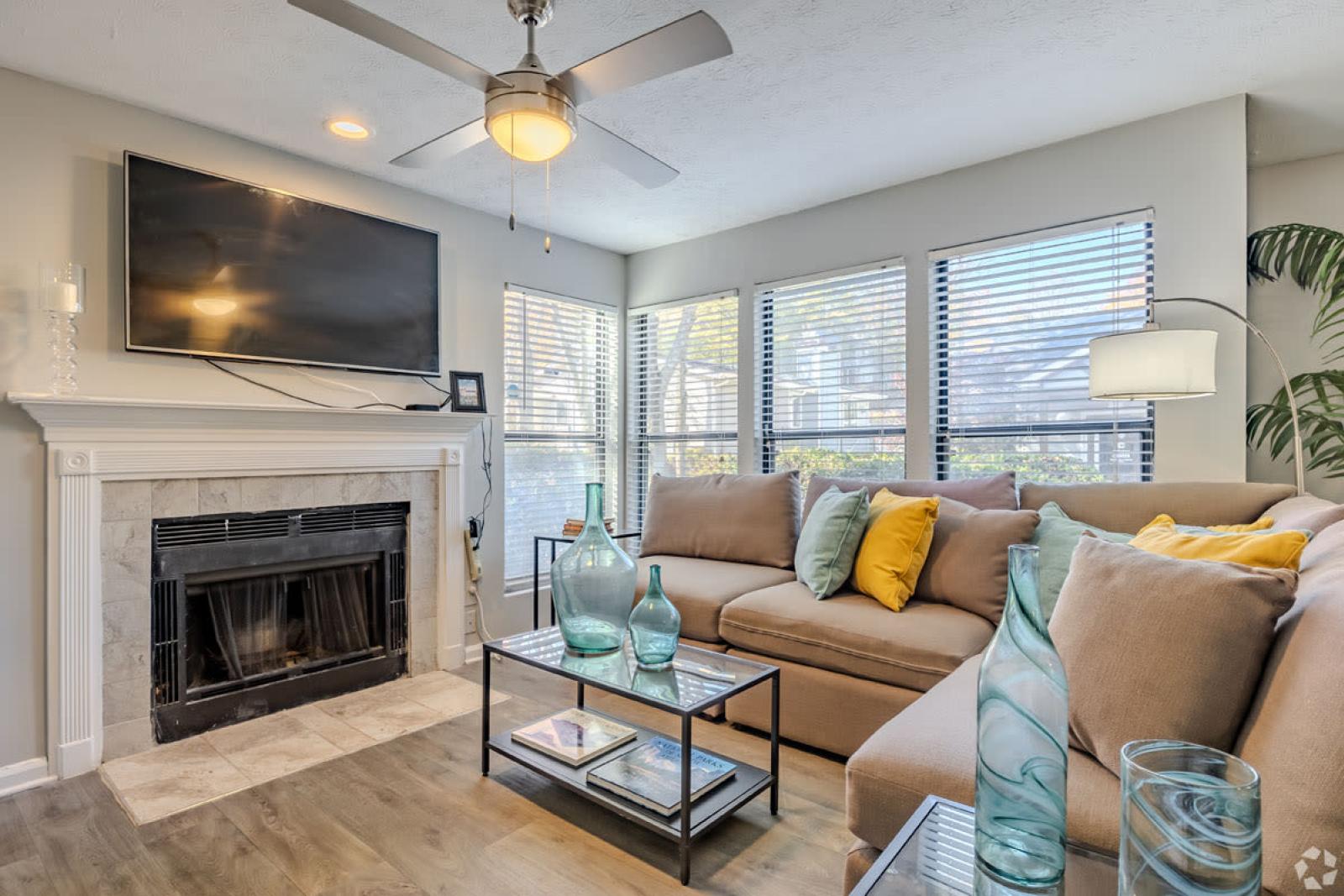 A cozy living room with a tiled fireplace, wall-mounted TV, and contemporary decor accents.