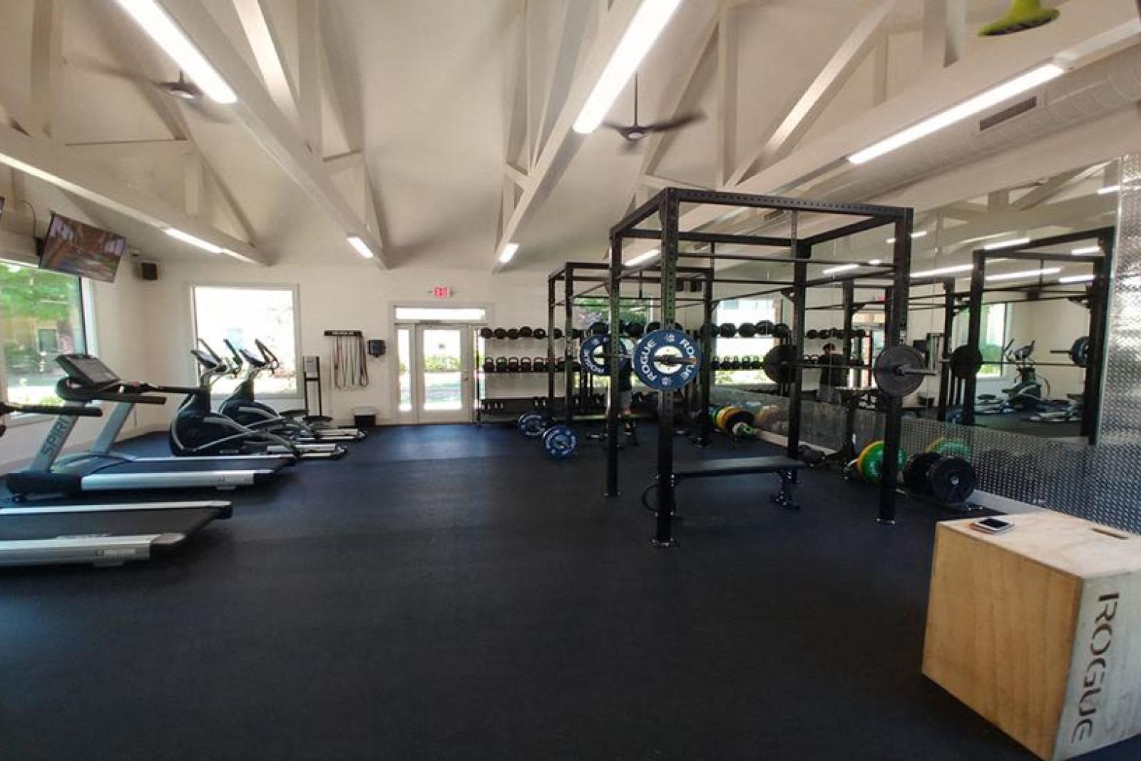 A spacious fitness center at Chatsworth Apartments in Chamblee, GA, featuring modern workout equipment, including treadmills, free weights, and power racks, under vaulted ceilings with natural light.