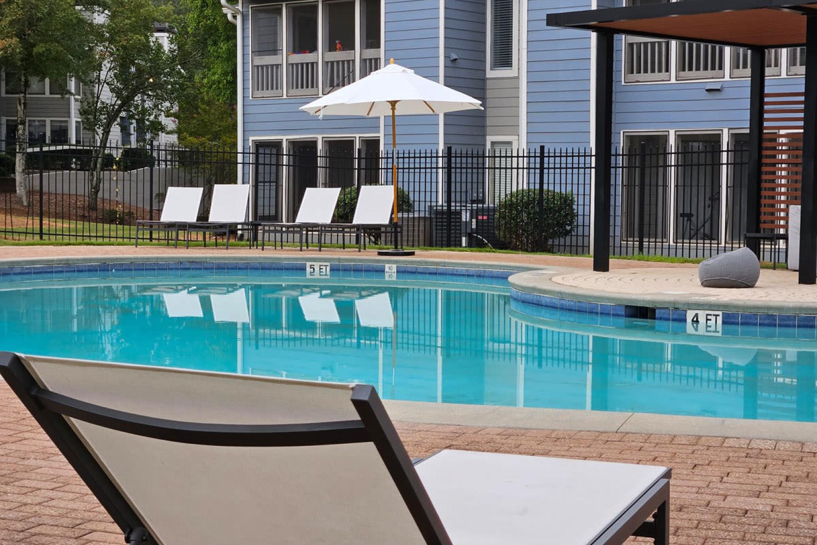 Refreshing poolside at Chatsworth Apartments with sun loungers and scenic views of the property.