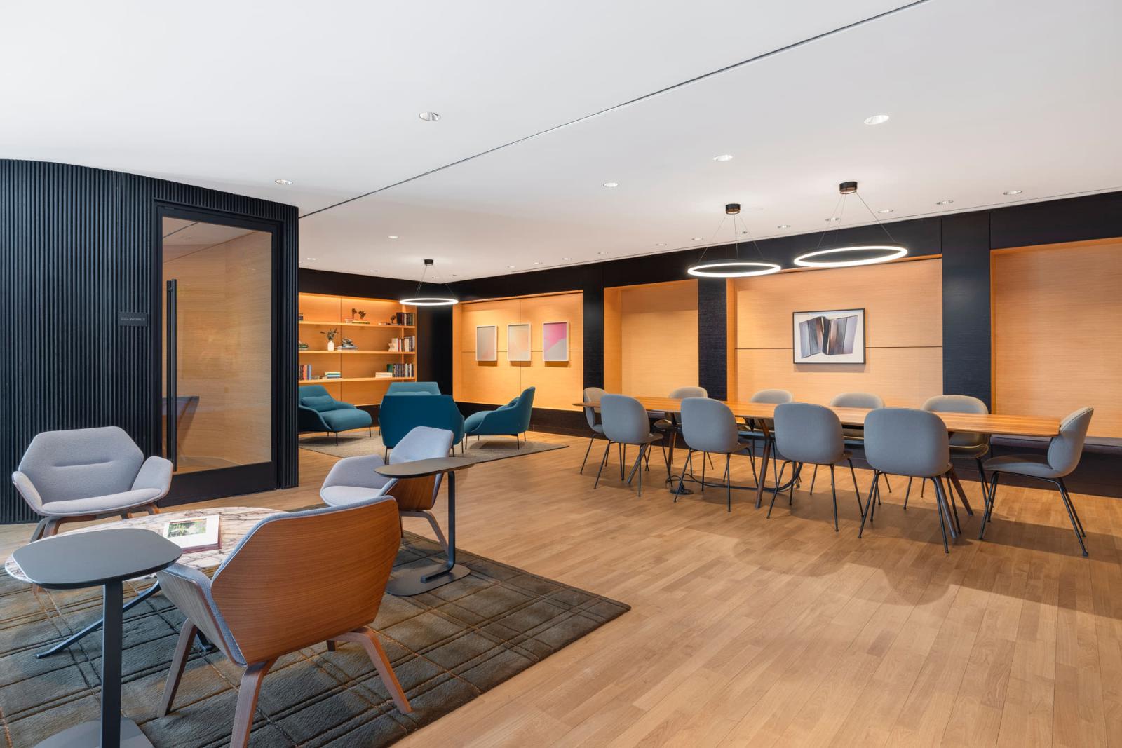 A private dining room with a round marble table, upholstered chairs, and warm wood tones, accented by a sculptural light fixture.