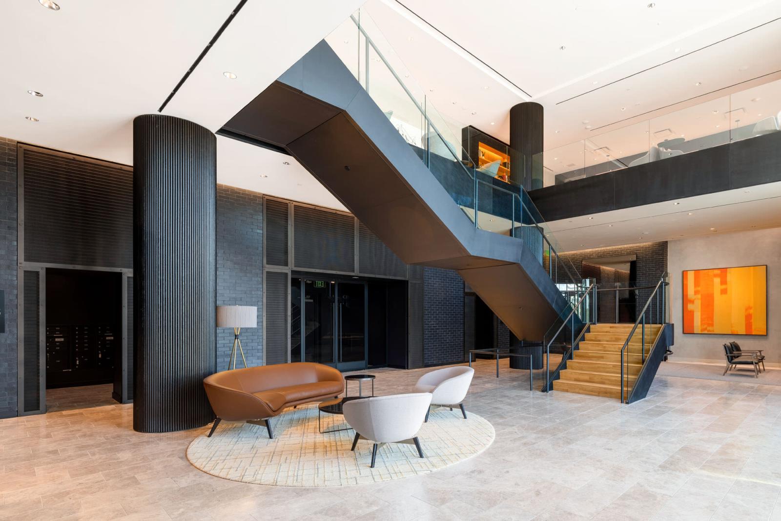 An elegant meeting space featuring a combination of blue and brown contemporary chairs, accent lighting, and a warm wooden floor.